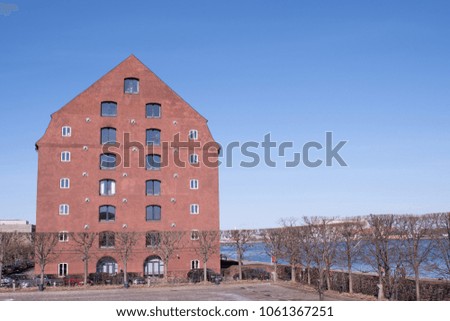 An old warehouse in Copenhagen along the waterfront under a clear blue sky