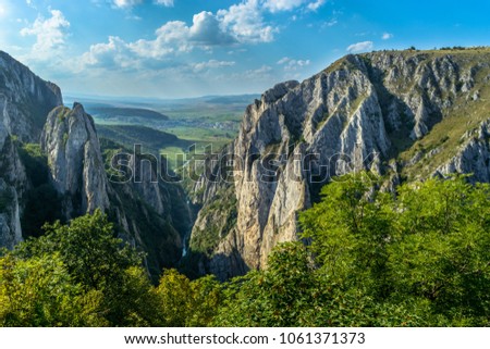 Scenic picture of the Gorge of Turda in Romania from higher elevation with rocky mountains, river and green vegetation