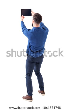 Rear back view of elegant handsome business man taking selfie photo with tablet. Full body isolated on white background.