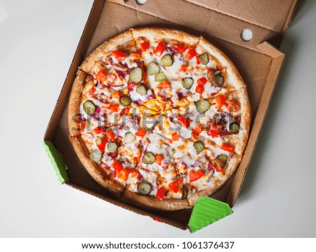 Cheeseburger pizza in delivery cardboard box on white table.
