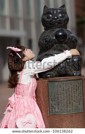 japanese lolita hugging cat statue in Tokyo