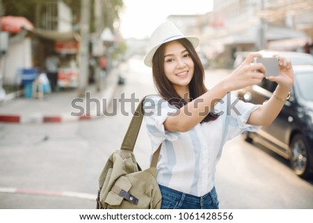 Young woman taking a photo with her phone on street in the city