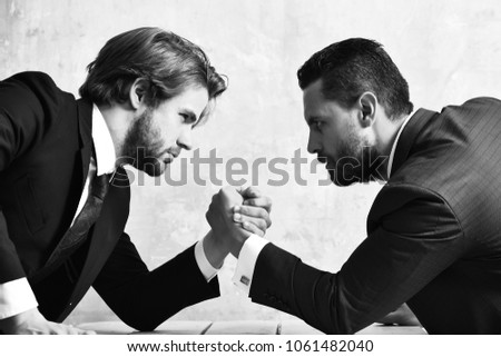 Conflict. Businessmen arm wrestling in suit in office