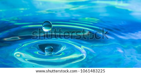 Blue water drop splash in a pond of clear water