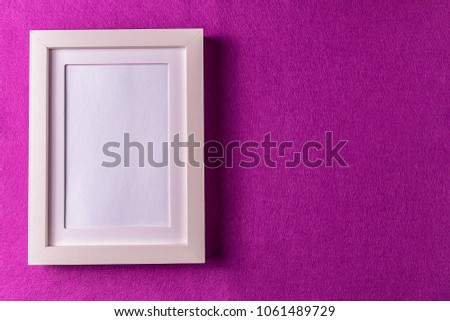 Minimalism style. White empty picture frame against; abstract colored paper background; flat lay.