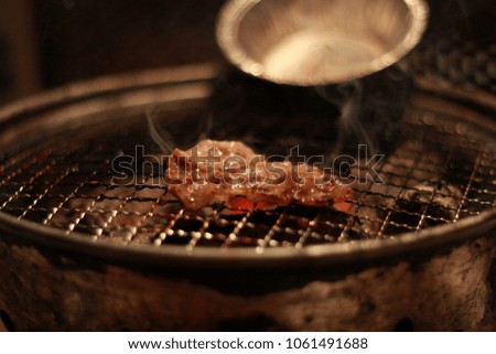 Japanese or korean grilled pork or beef slice on fire on burning charcoal with smoke