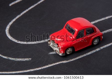 Toy car red color on the road chalked on black chalkboard