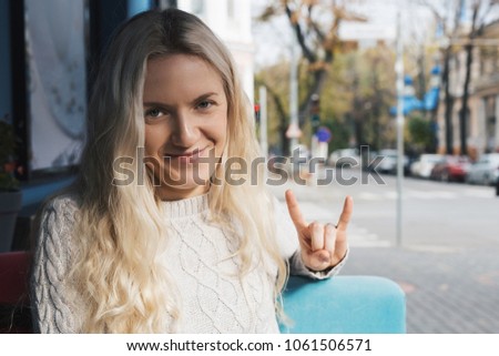 Young fashion woman sitting at the table in cafe. Stylish female model with blonde hairs
