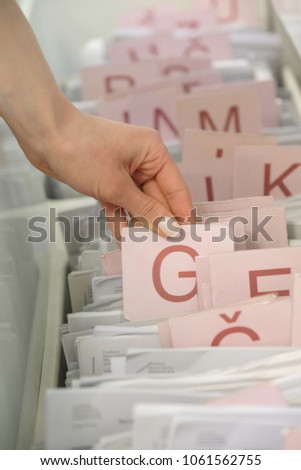 The hand of a woman choosing a medical record in the registry of the clinic