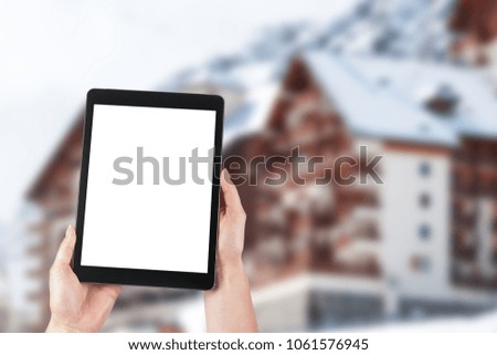 Ski resort and tablet with empty screen. Blank tablet screen with copy space.