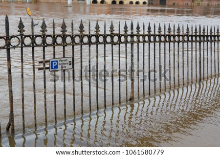 Railings  alongside the flooded River Ouse in York with a parking for permit holders only sign