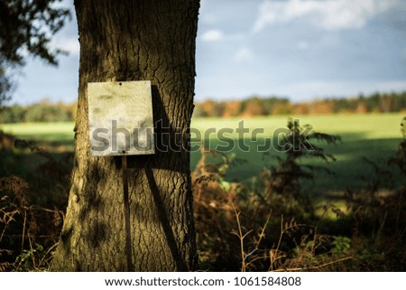Shooting Warning Blank Metal Sign in Countryside Leaning Against Tree Close Up