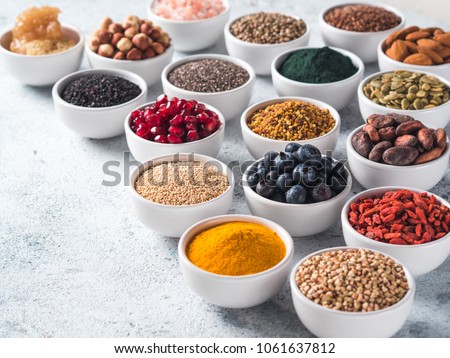 Various superfoods in smal bowl gray concrete background. Superfood as chia, spirulina, raw cocoa bean, goji, hemp, quinoa, bee pollen, black sesame, turmeric. Copy space for text. Royalty-Free Stock Photo #1061637812