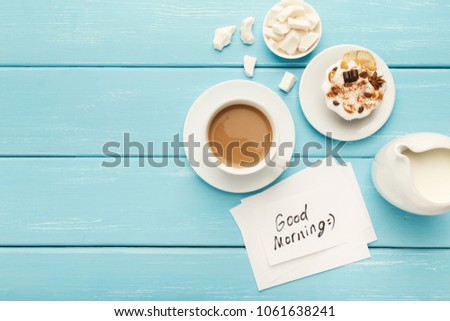 Coffee cup with cake and note Good morning on blue rustic table from above. Top view on cozy and tasty breakfast, copy space