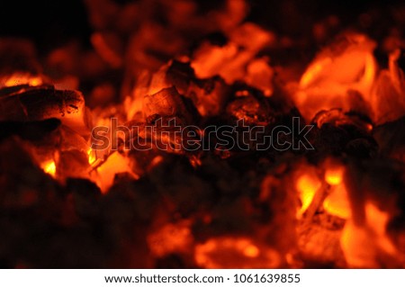 Burning charcoal in grill pit. Side view. Shallow depth of field. Briquettes Glowing In The BBQ Grill Pit. Dark flamy background. Coal for barbecue cooking.