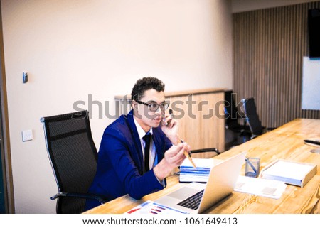 Successful man owner big company talking on mobile phone, sitting at workspace with open laptop computer and documents. Male skilled manager having cellphone conversation with client during work day