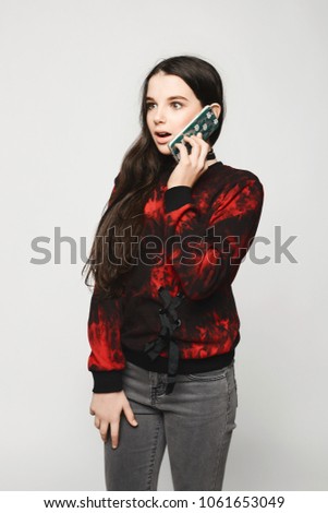 Young brunette teen girl with surprised face talking on the phone