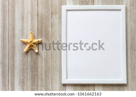 Mockup with white frame and star fish on a rustic wooden background with copy space