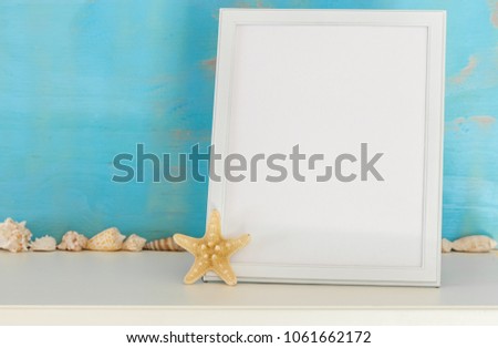 Mockup with white frame and star fish and sea shells on a turquoise rustic background
