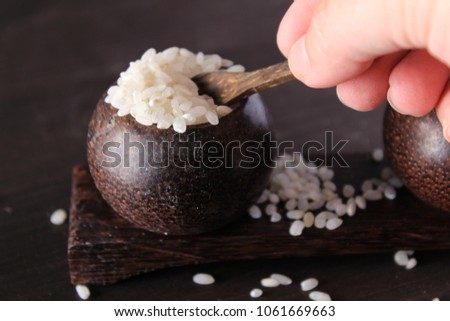 Small wooden bowls with white rice and hand holding a small spoon