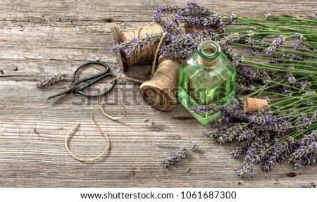 Lavender oil with fresh flowers on wooden background. Vintage style colored picture
