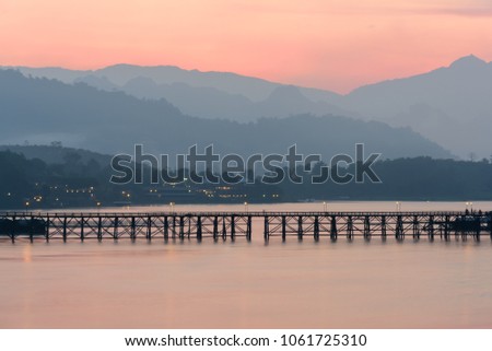 The old wooden bridge with mountain landscape at sunrise in Sangklaburi, Kanchanaburi Province, Thailand