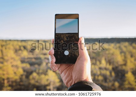 Close up of male hand holding smart phone and taking photo of landscape touchscreen display capture