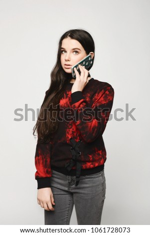 Young brunette teen girl talking on the phone, isolated on a white background