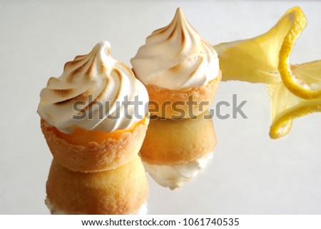 Mini lemon meringue tarts on a reflective background 