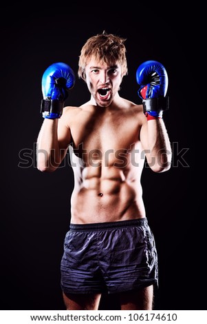 Portrait of an aggressive boxer in blue gloves posing at studio.