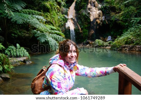 Young happy girl visiting a waterfall in Azores islands