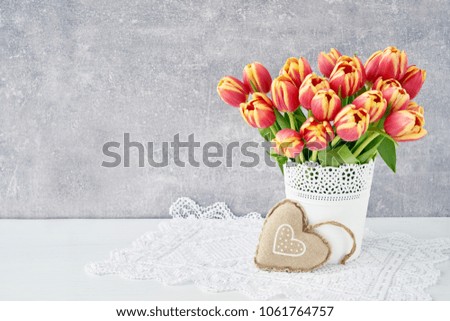Red tulips bouquet in white vase decorated with textile heart. Valentines Day, Mothers Day, birthday  concept. Copy space                               