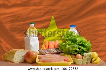 complete national flag of vietnam covers whole frame, waved, crunched and very natural looking. In front plan are fundamental food ingredients for consumers, symbolizing consumerism