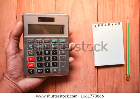 calculator, notepad with pencil on wood board background.using wallpaper for education, business 
photo.Take note of the product for book with paper and concept, object or copy space.