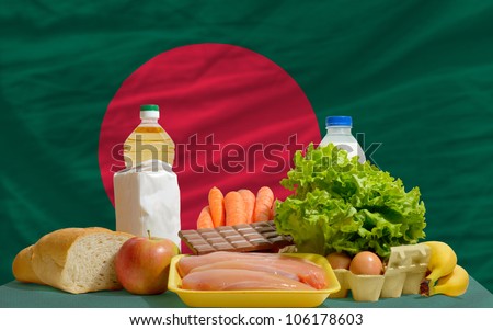 complete national flag of bangladesh covers whole frame, waved, crunched and very natural looking. In front plan are fundamental food ingredients for consumers, symbolizing consumerism
