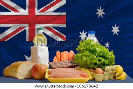complete national flag of australia covers whole frame, waved, crunched and very natural looking. In front plan are fundamental food ingredients for consumers, symbolizing consumerism