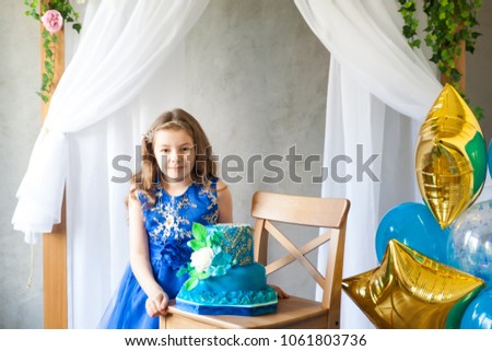 Birthday party in blue and gold collors. Studio session. Fashion girl celebrating her birthday. Girl with her birthday cake