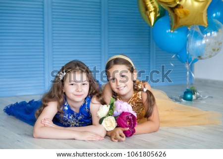 Birthday party in blue and gold collors. Studio session. Fashion girl celebrating her birthday. Two friends in blue and gold dress having fun