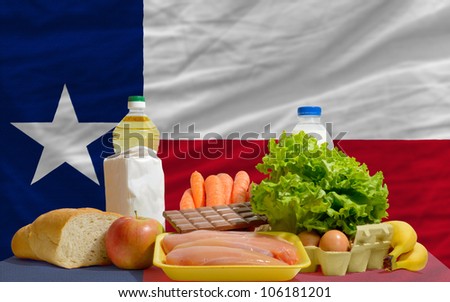 complete american state flag of texas covers whole frame, waved, crunched and very natural looking. In front plan are fundamental food ingredients for consumers, symbolizing consumerism