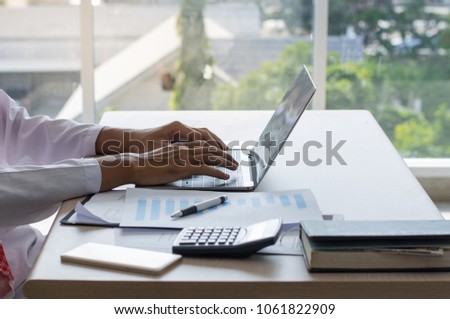 Close-up of male hands using modern laptop typing message on a laptop computer on the desk in the office