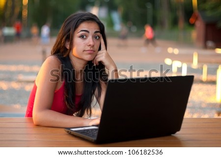 Beautiful girl thinking, looking and using her laptop with questioning facial expression.
