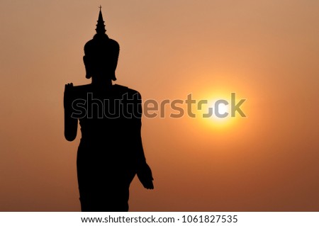 Silhouette picture of standing Buddha statue in the evening in outdoor park in Laos.