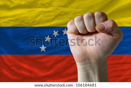 complete national flag of venezuela covers whole frame, waved, crunched and very natural looking. In front plan is clenched fist symbolizing determination