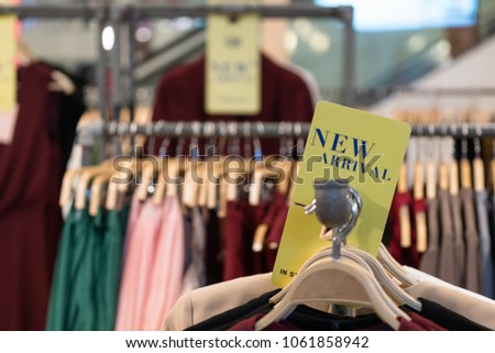 Clothes/shirt on wooden hanger with new arrival fashion tag/sign available in store. Latest cotton shirt for any season collection on rack at flea market/shop. Stall shopping apparel fashion concept.
