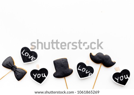 Men's birthday concept. Cookies in shape of moustache, hat, bow tie. Hearts with lettering love you on white background top view copy space