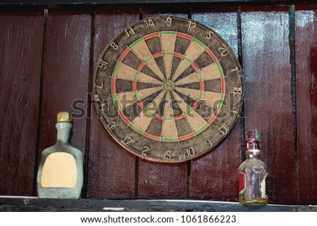 Old dart board and liquor bottleso on wooden wall