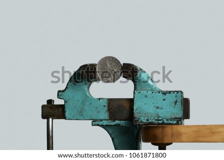 Pressure on the currency. Concept of currency under pressure. British Pound/Ten pence (GBP) coin being squeezed in jaw vice.