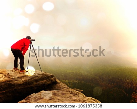 Abstract effect. Nature photographer prepare camera to takes impressive photos of misty fall mountains. Tourist photographer