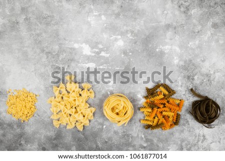 Various raw pasta on gray background. Top view, copy space. Food background