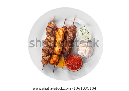 Shish kebab, beef, lamb, pork, chicken meat on the grill, barbecue, without garnish on a plate isolated on white background. Marinated onion, mayonnaise, tar tar, ketchup, tomato sauce View from above Royalty-Free Stock Photo #1061893184